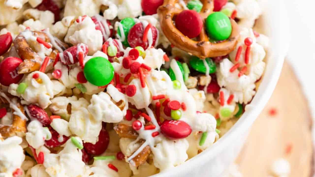 Christmas popcorn in a white bowl with pretzels.