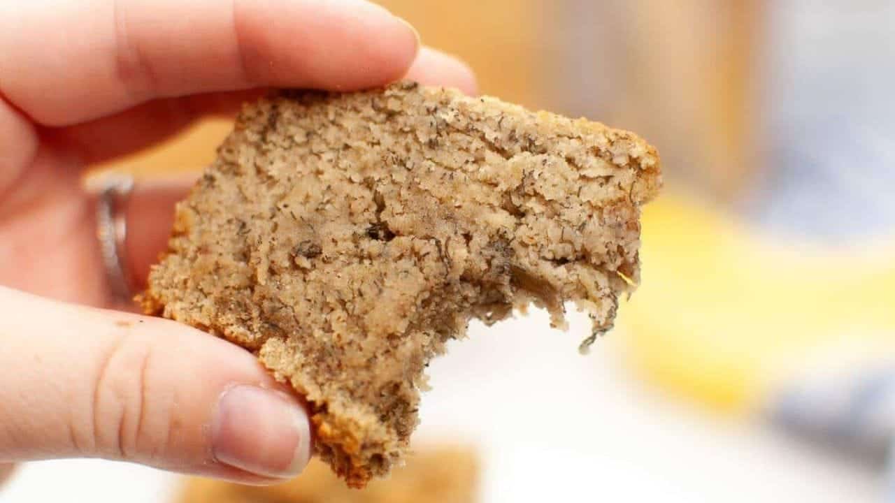 A hand holding a partially eaten slice of banana bread.