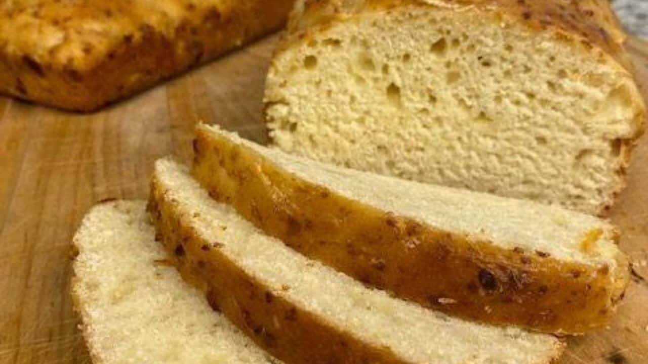 Loaf of cottage cheese bread with two slices resting on wooden board.