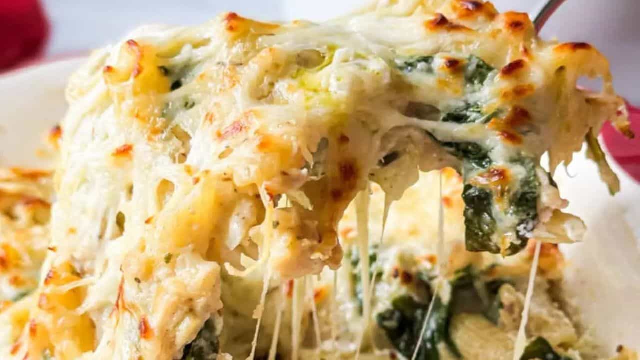Penne and chicken in a casserole dish with pesto and cheese.