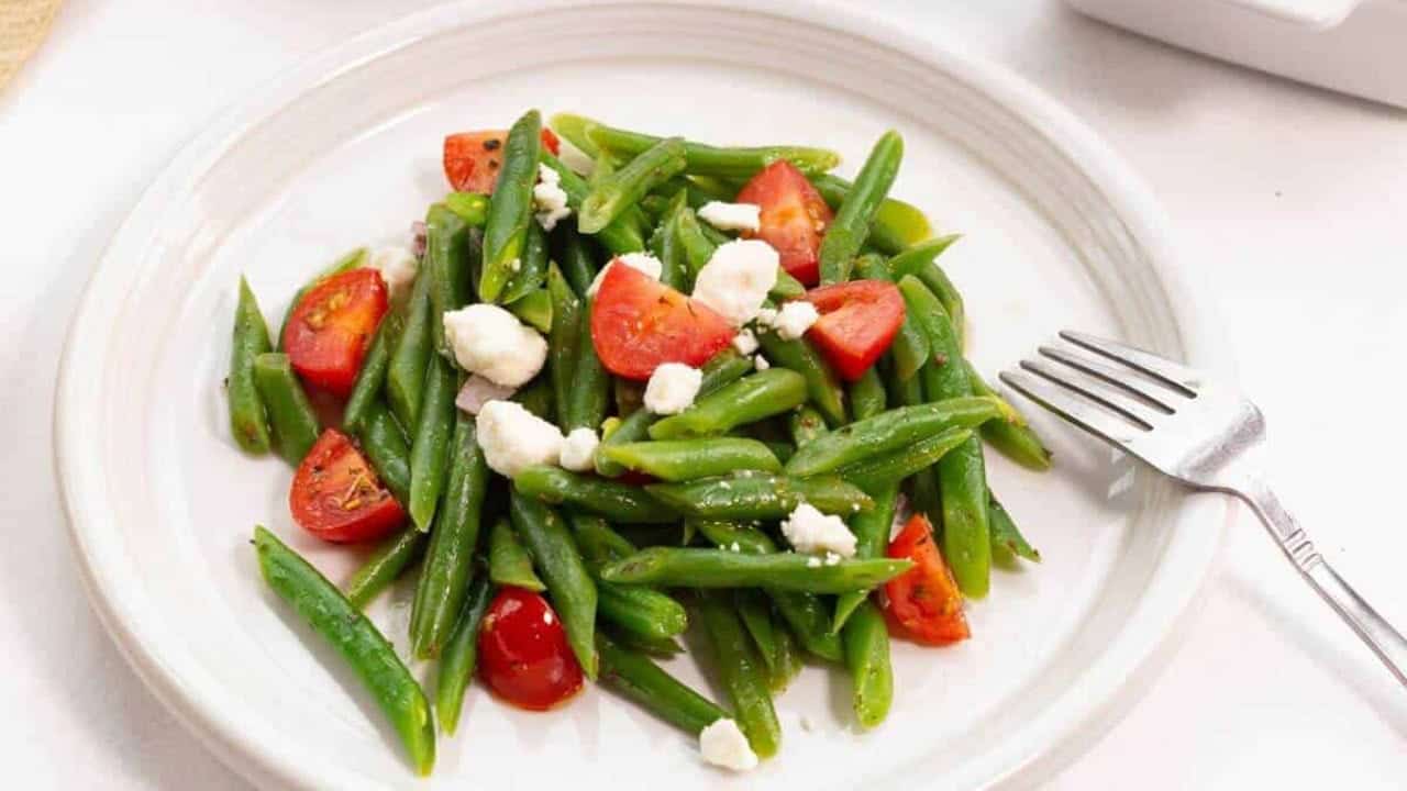 Green beans and tomatoes on a white plate.