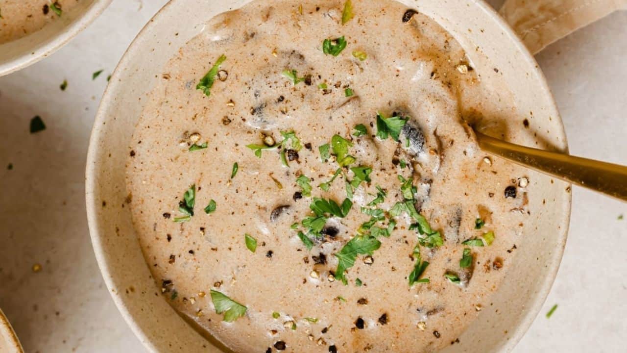 A bowl of Hungarian mushroom soup with a gold spoon.