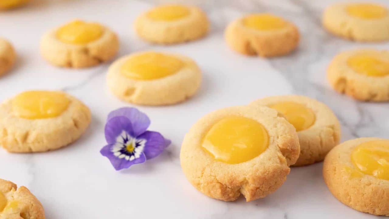 Close up view of lemon curd cookies with a lavender flower in background.