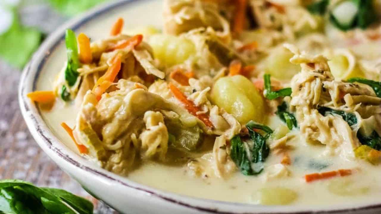 Bowl of copycat Olive Garden chicken gnocchi soup in a bowl with breadsticks in the background.