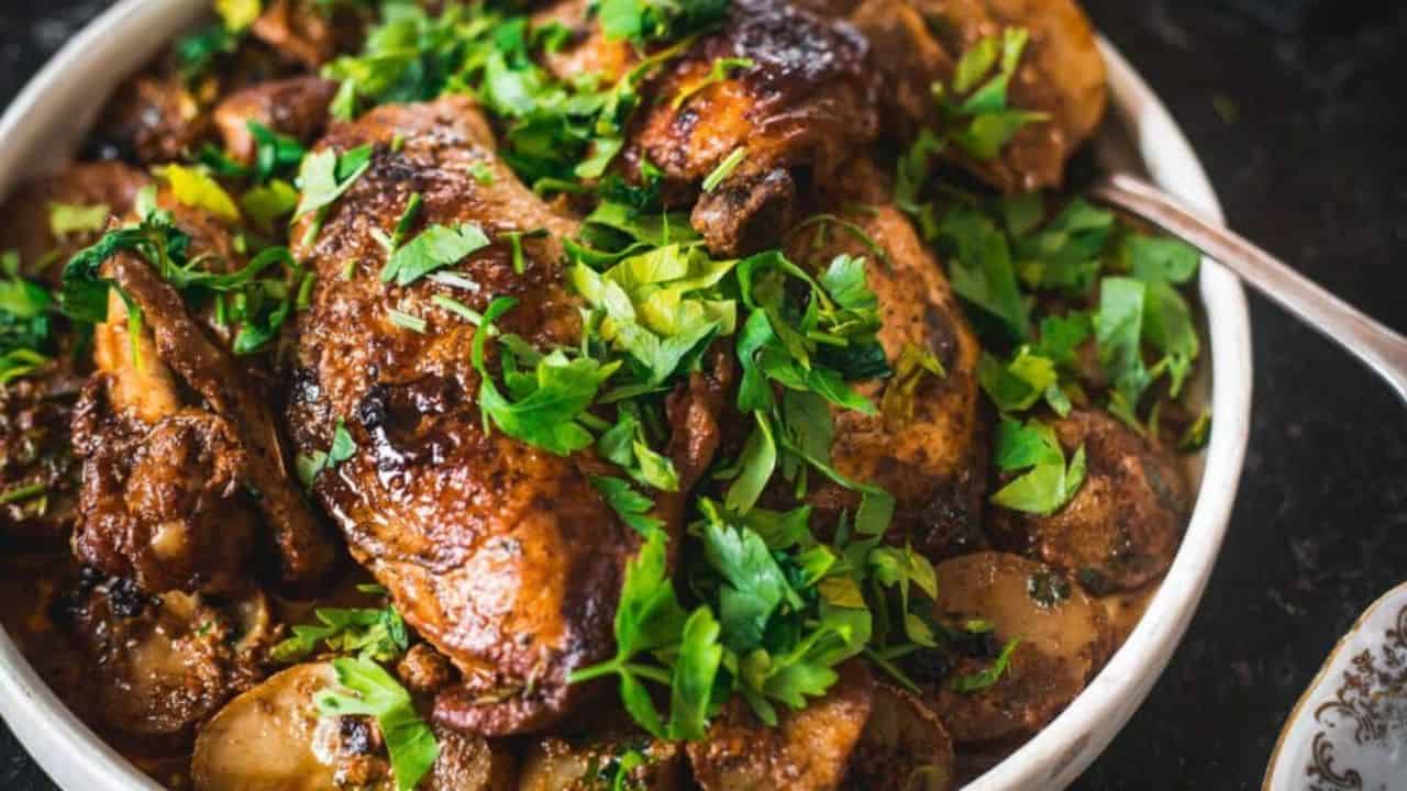 Roasted chicken with parsley and potatoes on a plate.