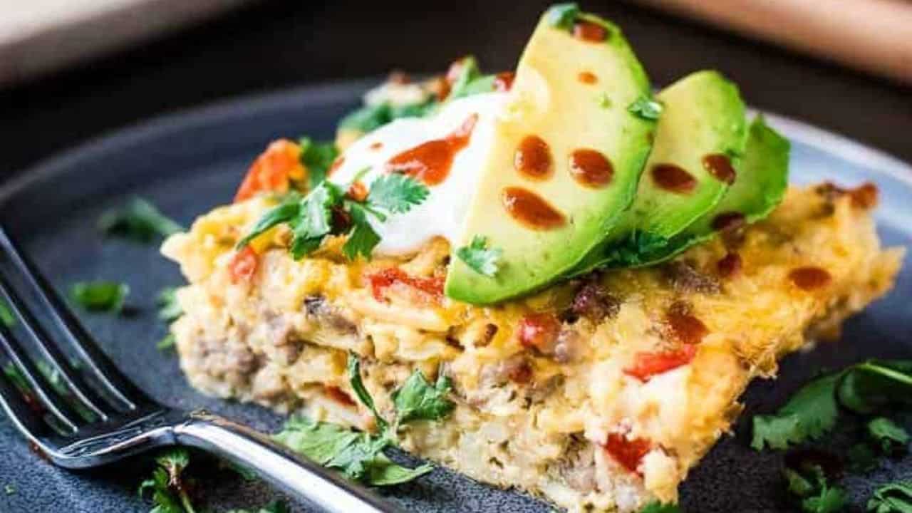An overhead shot of breakfast casserole next to a single serving and a toppings bar.