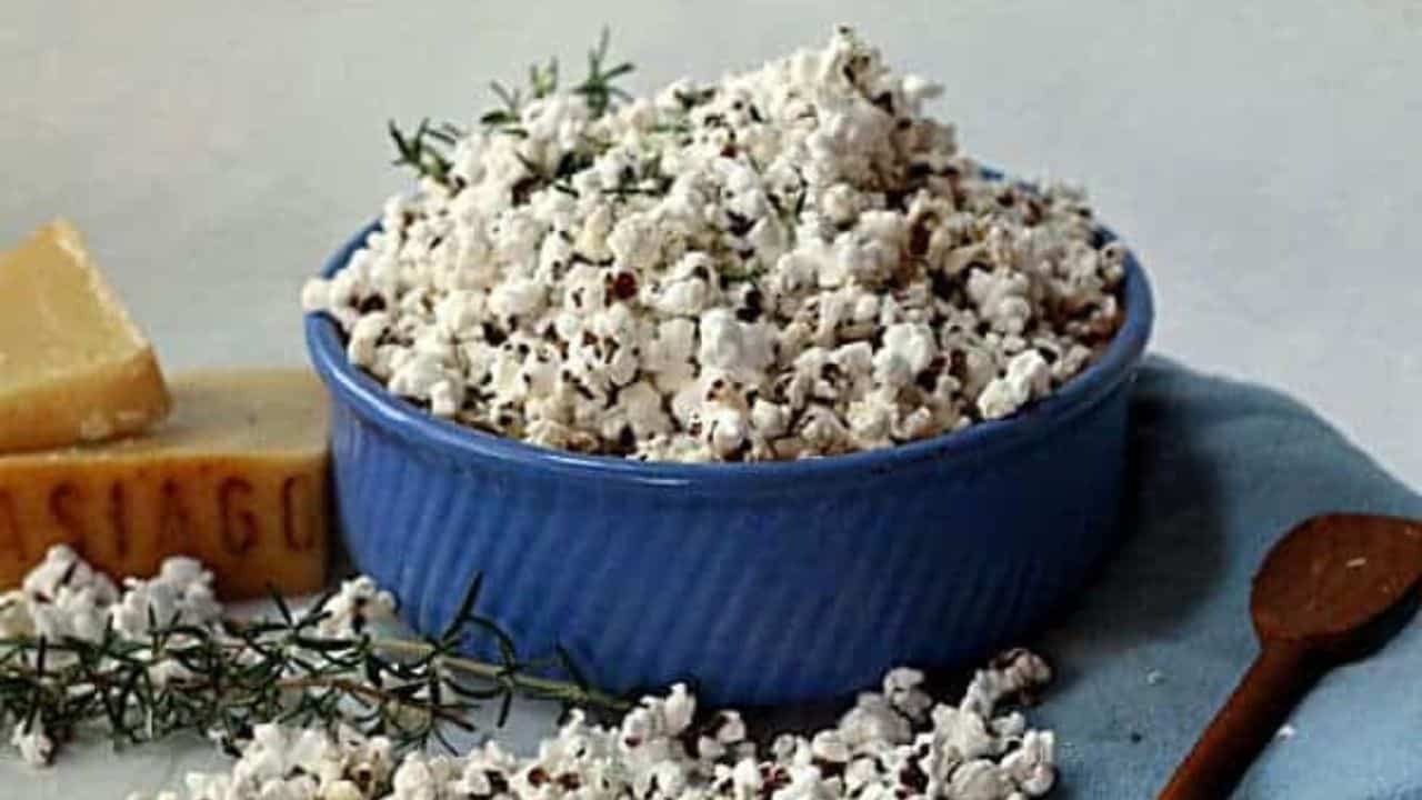 Popcorn with rosemary and Asiago cheese in a blue bowl.
