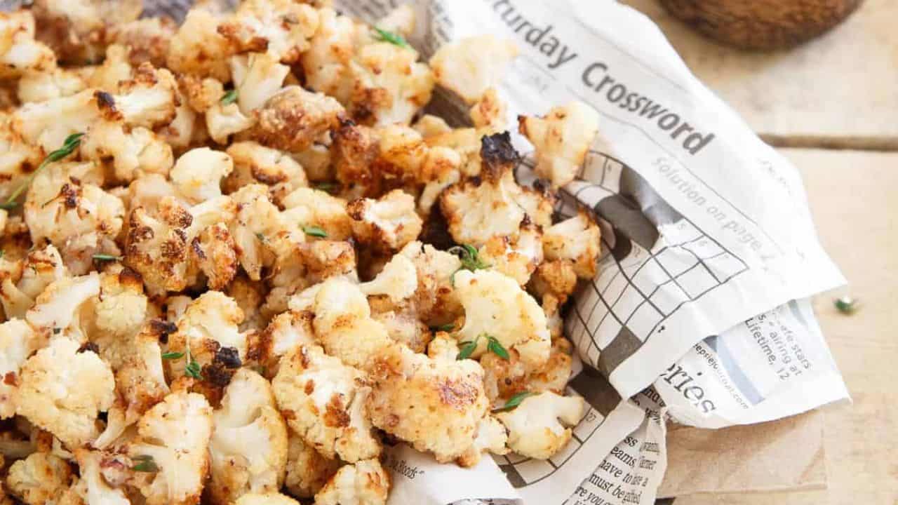 Salt and vinegar popcorn cauliflower in a newspaper covered bowl.