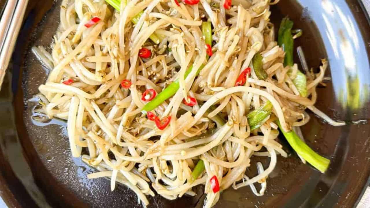 Fresh and crunchy mung bean sprouts stir-fried dish on a black plate.