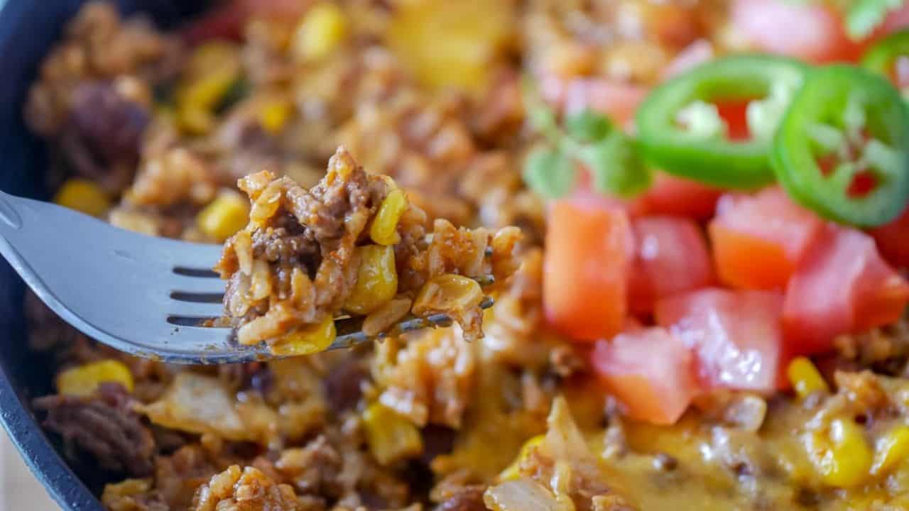 Closeup of a skillet with ground beef, cheese and tomatoes.