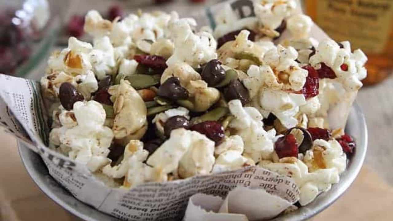 Trail mix popcorn in a bowl lined with newspaper.