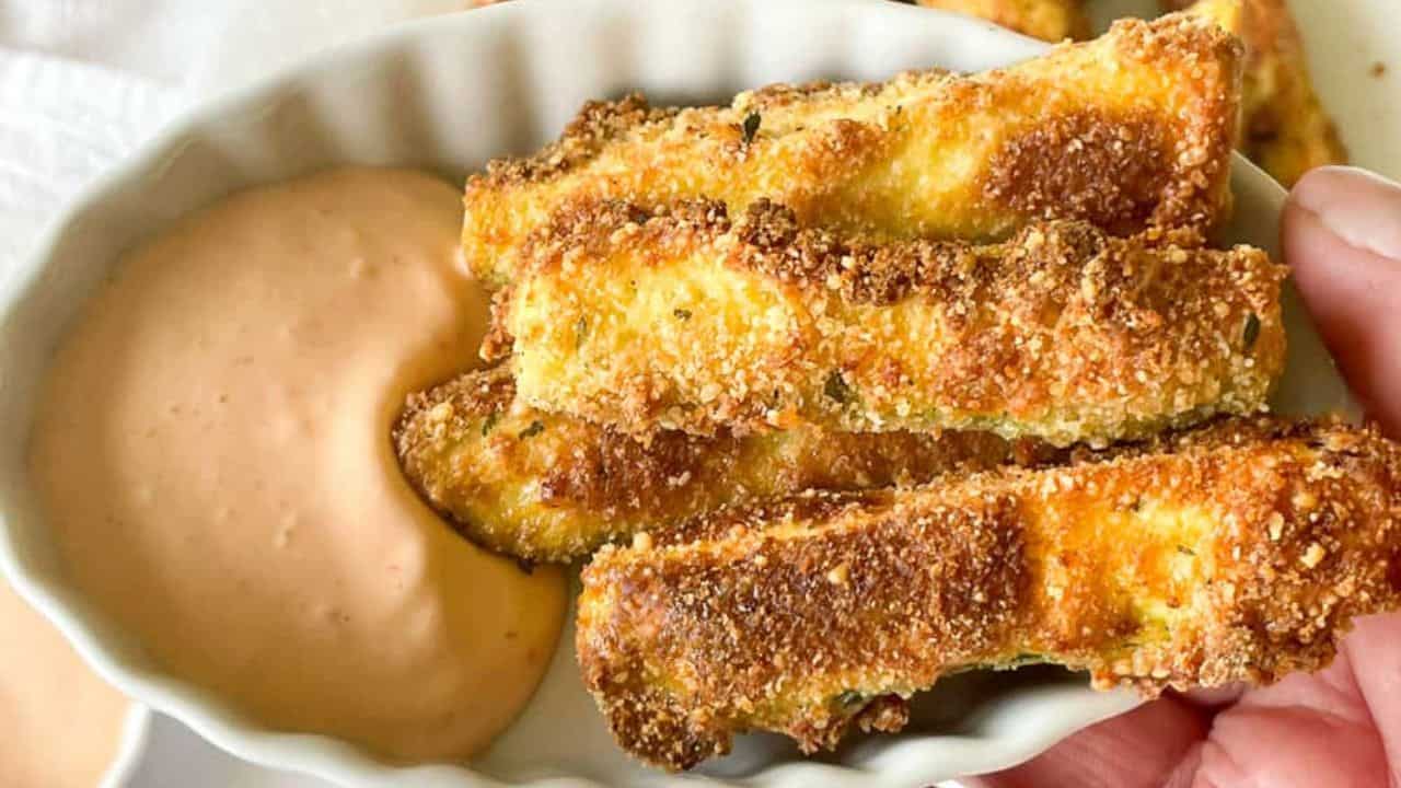 Crispy air fryer zucchini fries in a dish with aioli.