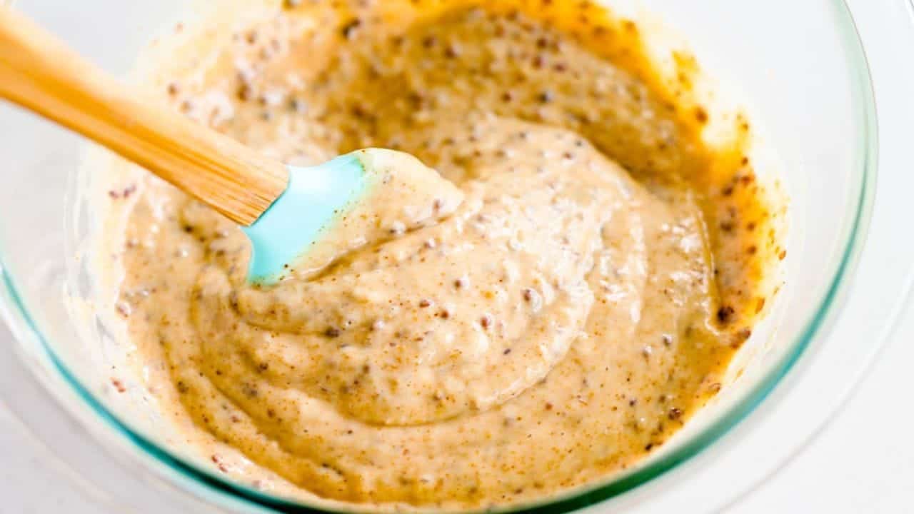 An onion ring being dipped into Spicy Dipping Sauce.