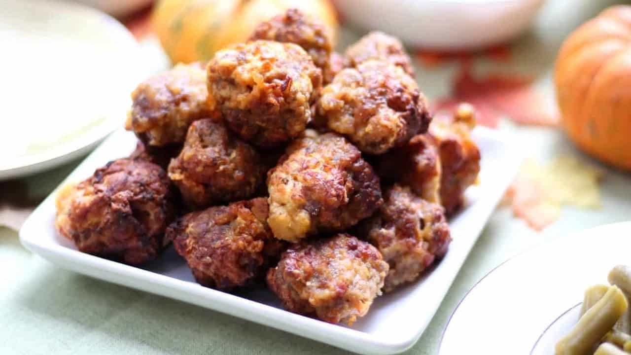 White plate of sausage balls on a Thanksgiving themed table.