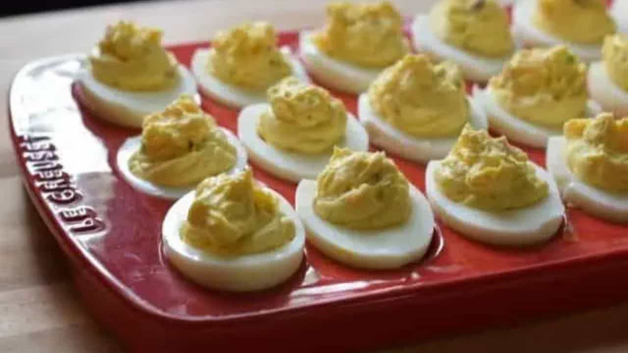 Image shows bacon deviled eggs in a red tray.