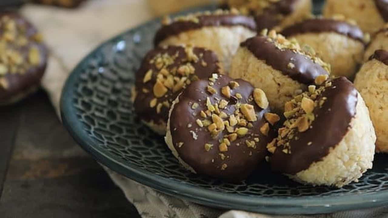 A plate of cookies with chocolate and pistachios on it.