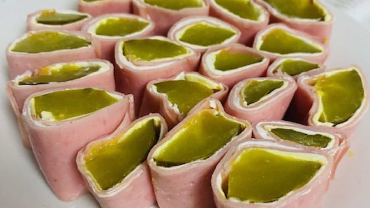Overhead view of cream cheese pickle wraps on white plate.