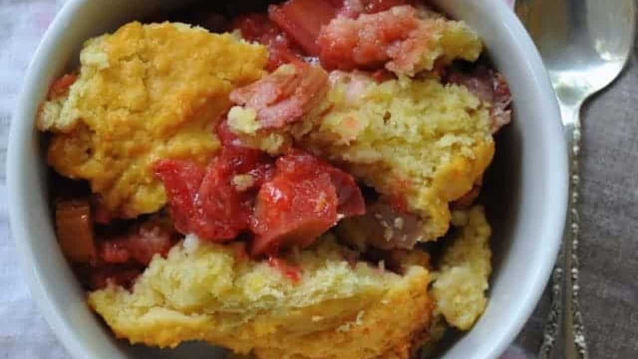 Close-up photo of strawberry rhubarb cobbler with spoon on the side.