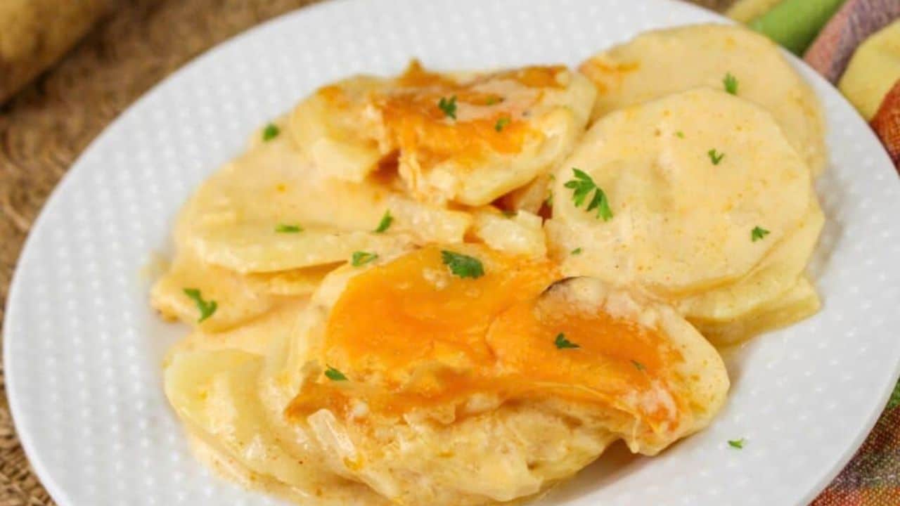 A white plate with cheesy potatoes, garnished with parsley.