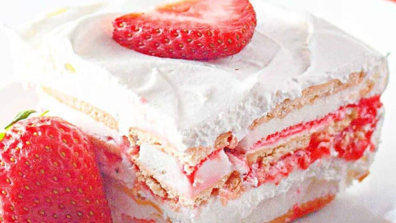 A slice of strawberry ice cream cake, topped with a fresh strawberry.