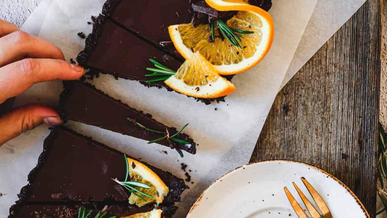 A chocolate tart with orange slices and rosemary.