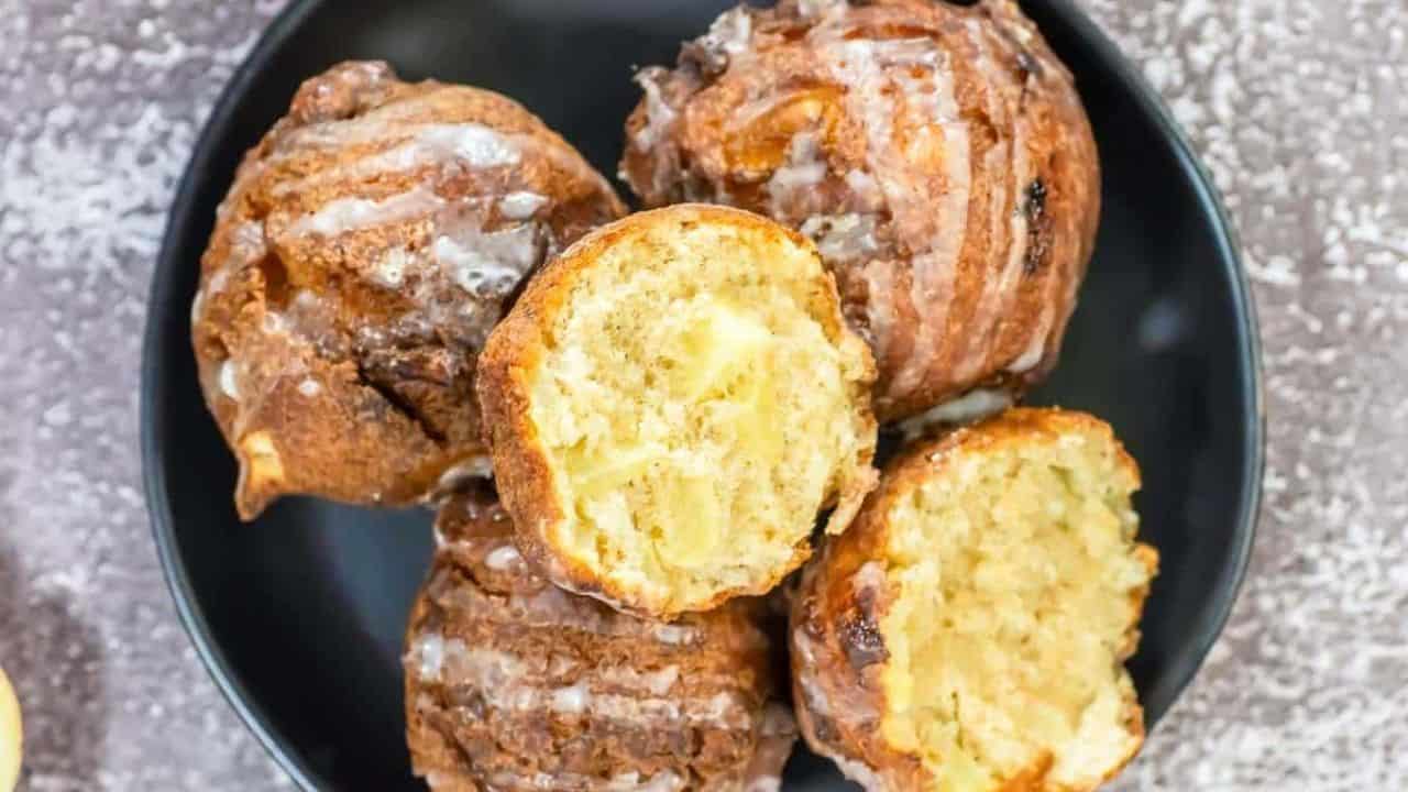 Overhead view of a black plate with glazed apple fritters.