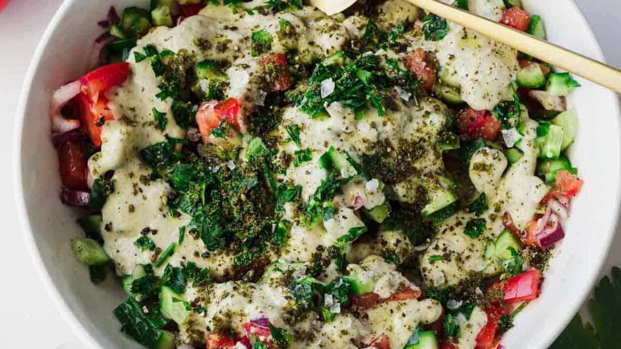Israeli chopped salad in a white bowl with diced tomatoes, cucumbers, and herbs.