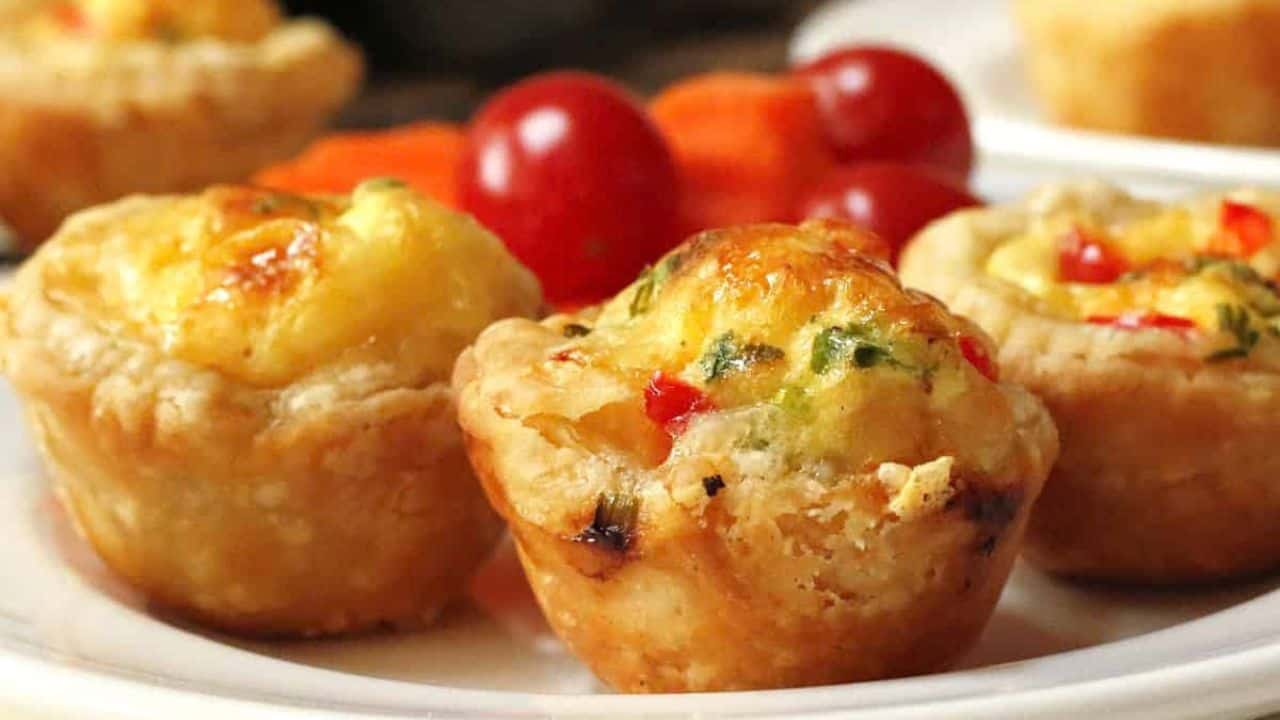 Mini Swiss cheese quiches on a white platter.