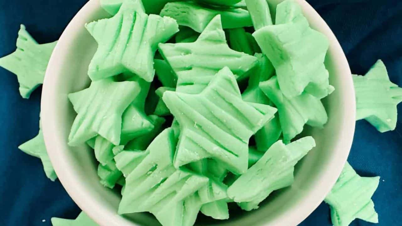 A bowl full of green star shaped mints.