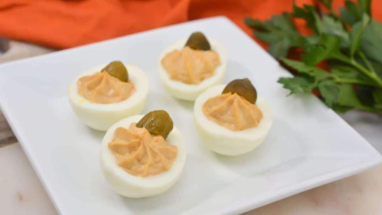Pumpkin deviled eggs on a white plate.