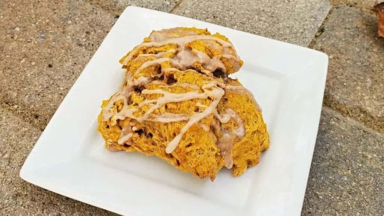 Image shows Three pumpkin scones on a plate with icing.