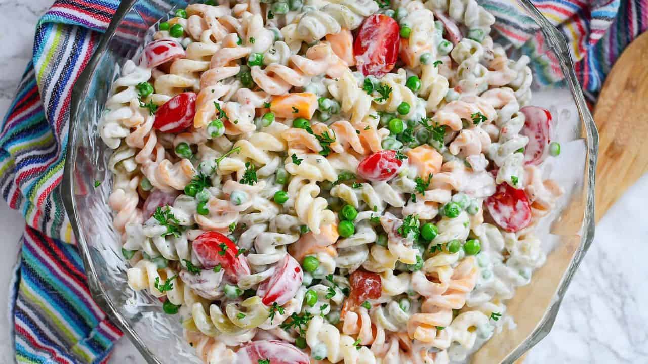 Bacon ranch pasta salad in a clear bowl with a striped towel.